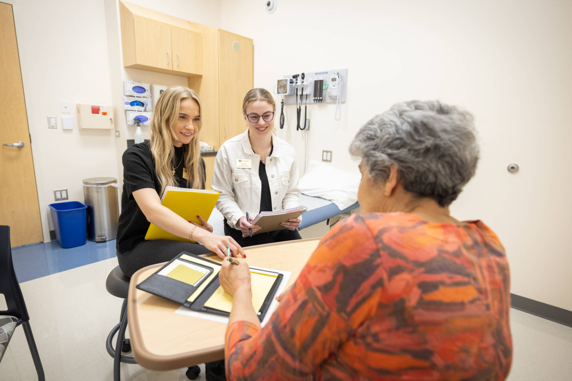 two students assisting an older adult